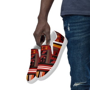 May include: A pair of white canvas slip-on shoes with a red, black, yellow, and orange geometric pattern.