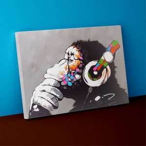 May include: A colourful painting of a monkey wearing headphones. The monkey's face is covered in colourful dots and the headphones are bright red, blue, green, and yellow.