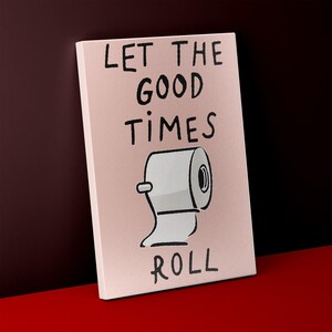 May include: A canvas print with the phrase "LET THE GOOD TIMES ROLL" in black lettering. A cartoon illustration of a roll of toilet paper is below the text, on a pink background.
