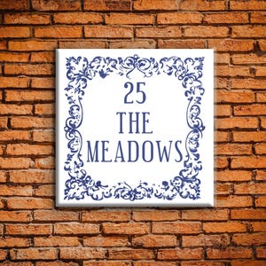 May include: White ceramic tile with a blue decorative border. The tile has the number 25, the words "The Meadows" and a decorative border.