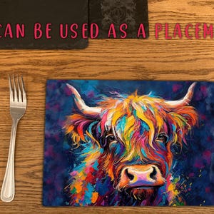May include: A colorful abstract painting of a Highland cow with a blue background. The cow's fur is painted in shades of pink, yellow, orange, and green. The painting is on a rectangular piece of glass, which can be used as a placemat.