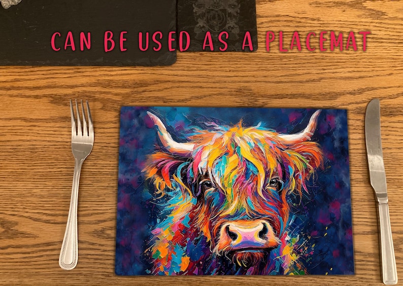 May include: A colorful abstract painting of a Highland cow with a blue background. The cow's fur is painted in shades of pink, yellow, orange, and green. The painting is on a rectangular piece of glass, which can be used as a placemat.