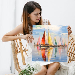 Pode incluir: Uma pintura colorida de veleiros em um mar azul calmo com um c&eacute;u brilhante. Os veleiros s&atilde;o de v&aacute;rias cores, incluindo vermelho, amarelo, azul e verde. A pintura &eacute; emoldurada e est&aacute; sendo segurada por uma pessoa.