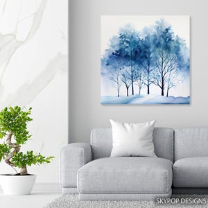 May include: A watercolor painting of a group of trees in shades of blue. The artwork features a winter scene with bare branches and a snowy ground. The painting is displayed on a wall above a gray sofa. The text "SKYPOP DESIGNS" is in the bottom right corner.