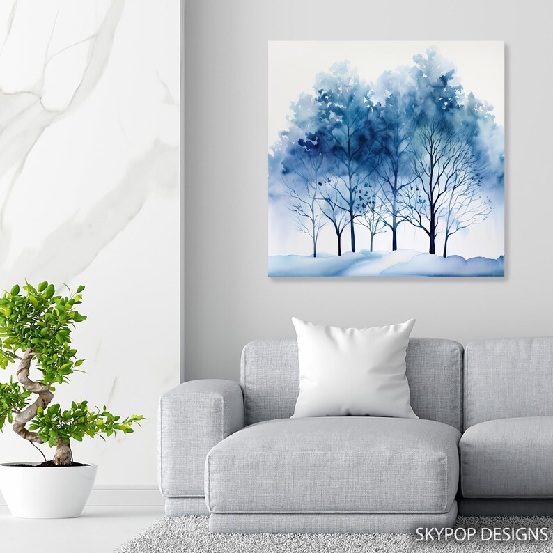 May include: A watercolor painting of a group of trees in shades of blue. The artwork features a winter scene with bare branches and a snowy ground. The painting is displayed on a wall above a gray sofa. The text "SKYPOP DESIGNS" is in the bottom right corner.