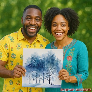 May include: A couple smiles while holding a square watercolor painting of blue trees. The painting has a white border and is set against a green background. The woman wears a teal top with floral embroidery. The man wears a yellow shirt with a floral pattern. The painting has the text "SKYPOP DESIGNS" in the bottom right corner.