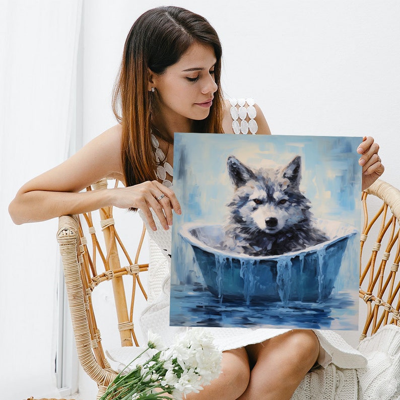 May include: A woman is holding a painting of a wolf sitting in a blue bathtub. The wolf is grey and white with blue eyes. The bathtub is filled with blue water and has a white rim. The background of the painting is a light blue sky with white clouds.