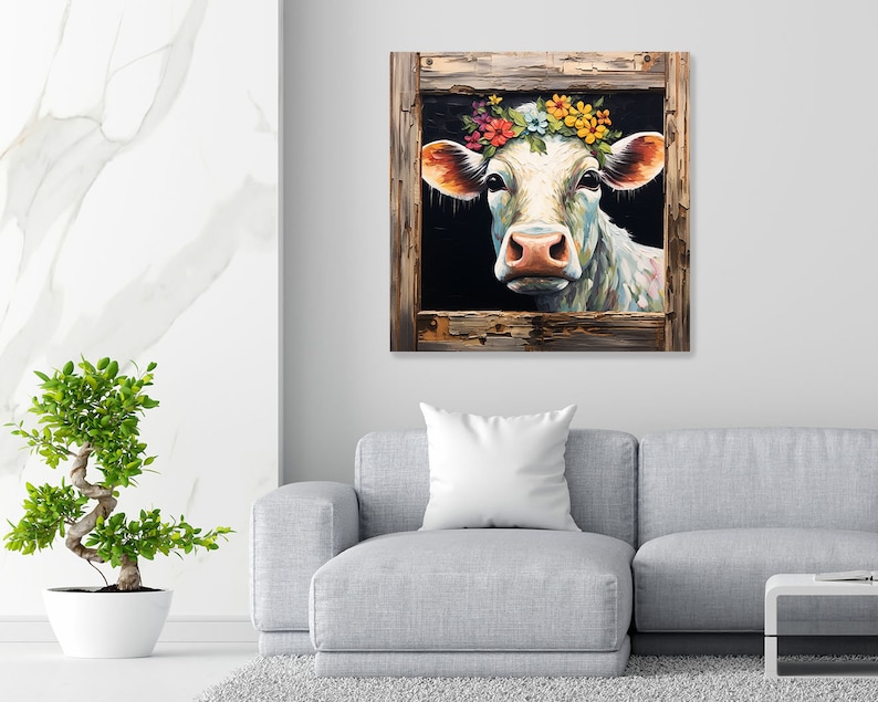 May include: A white cow with a colorful flower crown looks out from a rustic wooden frame. The cow's eyes are closed and its mouth is slightly open, as if it is smiling. The background is a dark blue color.