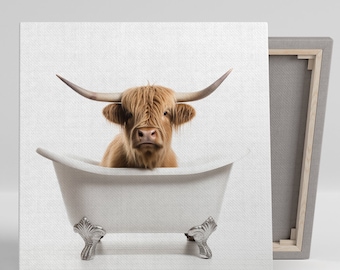 May include: Canvas art print featuring a Highland cow in a white clawfoot bathtub. The cow has long, shaggy, light brown fur and large horns. The bathtub has ornate silver feet. The canvas is stretched over a wooden frame.