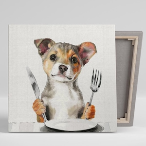May include: A brown, white, and black puppy dog with big ears sits at a table with a white plate and a fork and knife. The dog is looking at the camera with a curious expression.