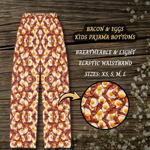 May include: Pajama bottoms featuring an all-over print of fried eggs and bacon strips. The garment includes an elastic waistband and is described as breathable and light. Text on the image reads: Bacon & Eggs Kids Pajama Bottoms.