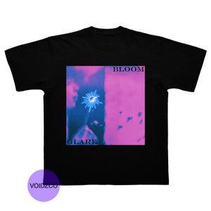 Puede incluir: Camiseta negra con un estampado gráfico de una persona soplando un diente de león con un brillo azul. El texto "BLOOM" y "GLARE" está impreso en el gráfico.