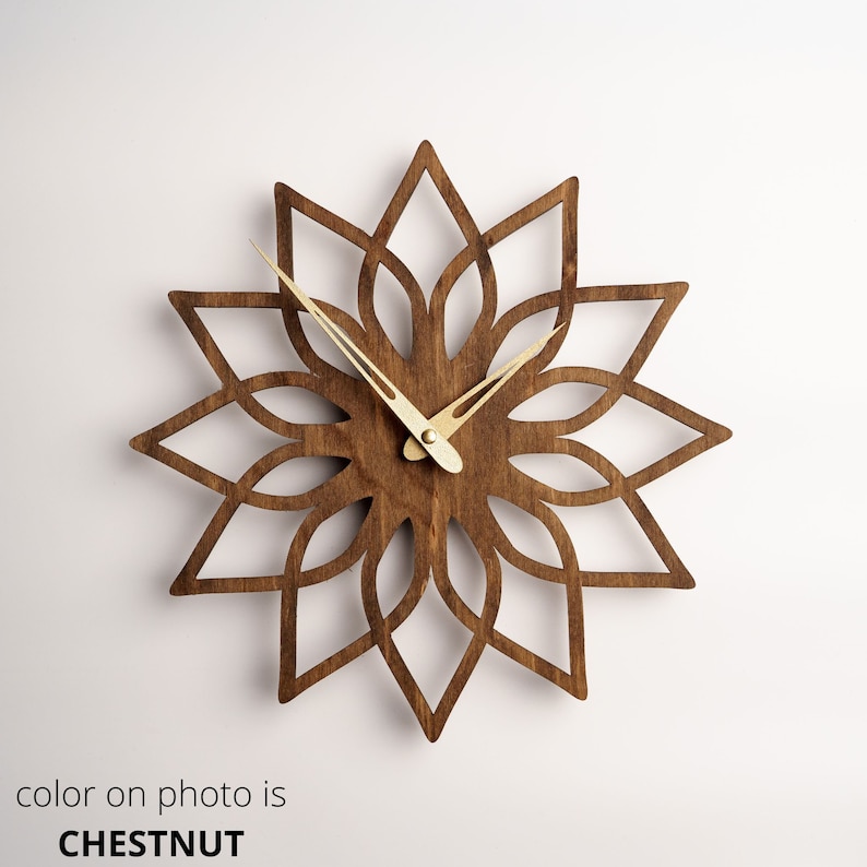 K&ouml;nnte beinhalten: Eine kastanienfarbene Wanduhr aus Holz mit floralem Design. Die Uhr hat eine sternf&ouml;rmige Form mit aufwendigen Ausschnitten und goldfarbenen Zeigern. Der Text "color on photo is CHESTNUT" befindet sich unten.