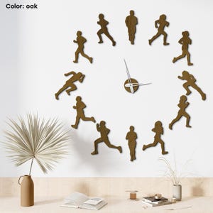 Puede incluir: Reloj de pared color roble con figuras de corredores dispuestas en círculo. Las manecillas del reloj son plateadas y el texto "Color: oak" es visible. El reloj está montado en una pared blanca.