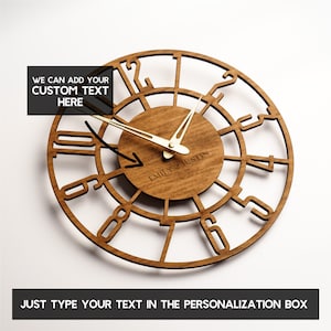 May include: A wooden wall clock with a circular design. The clock features Roman numerals and gold-colored hands. The center of the clock has the text "EMILY & JUSTIN EST 2016". The text "WE CAN ADD YOUR CUSTOM TEXT HERE" and "JUST TYPE YOUR TEXT IN THE PERSONALIZATION BOX" are also visible.