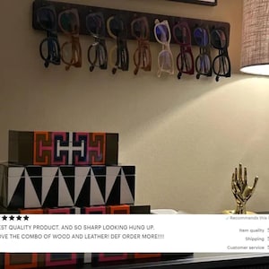 May include: A dark wooden rack displays a collection of eyeglasses with various frame colors. Below, stacked decorative boxes feature geometric patterns in black, white, and vibrant hues. A gold hand sculpture adds a touch of elegance.