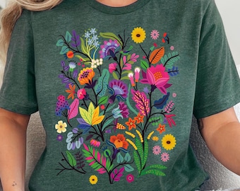 May include: A heather forest green short-sleeve t-shirt featuring a vibrant, multi-colored floral graphic print on the front. The design includes various stylized flowers and leaves in shades of pink, yellow, orange, purple, and blue.