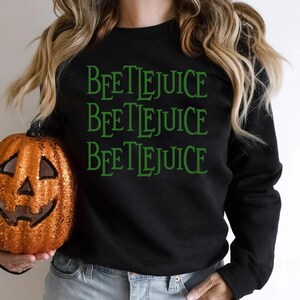 May include: Black sweatshirt with the words "Beetlejuice" repeated three times in green text.
