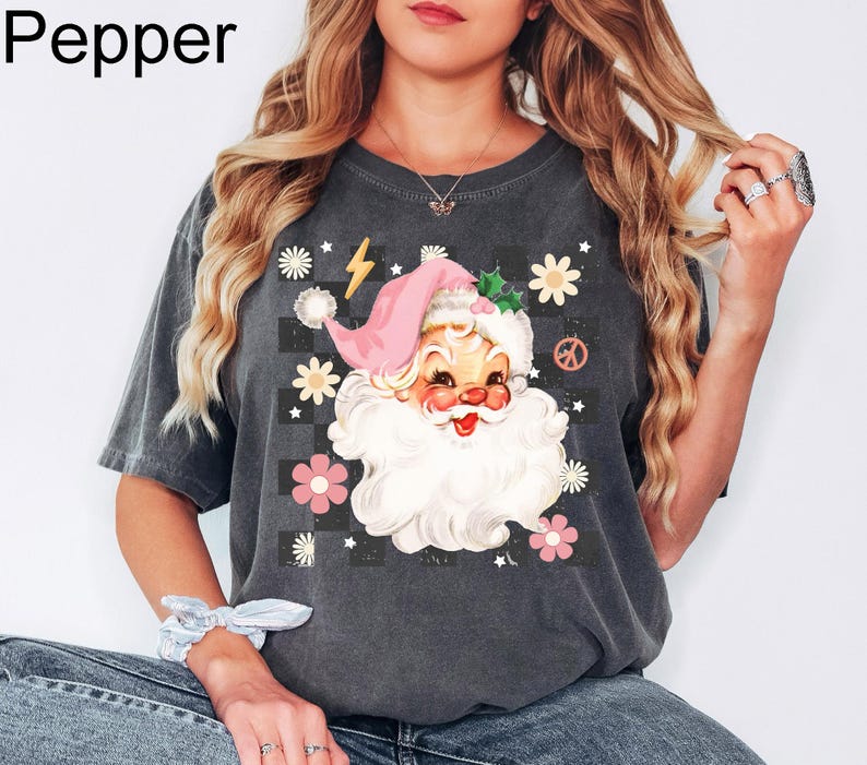 May include: Dark gray t-shirt featuring a Santa Claus graphic with a pink hat and white beard, surrounded by flowers and a peace sign. The word "Pepper" is in the top left corner.