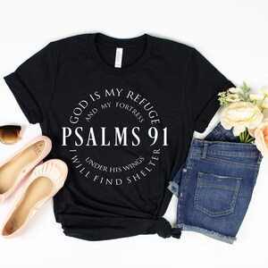 May include: Black t-shirt with white text that reads "God is my refuge and my fortress Psalms 91 Under his wings I will find shelter".