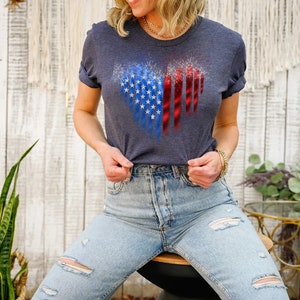 Pu&ograve; includere: Una maglietta blu navy con un design a forma di cuore raffigurante la bandiera americana. Il design incorpora le stelle e le strisce in uno stile patriottico. La maglietta &egrave; realizzata in materiale morbido, adatta per un abbigliamento casual.