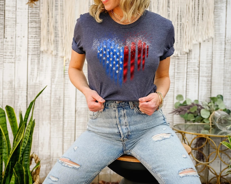 Pu&ograve; includere: Una maglietta blu navy con un design a forma di cuore raffigurante la bandiera americana. Il design incorpora le stelle e le strisce in uno stile patriottico. La maglietta &egrave; realizzata in materiale morbido, adatta per un abbigliamento casual.