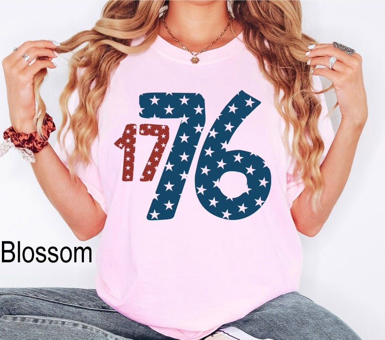 Puede incluir: Camiseta rosa con un gr&aacute;fico azul y rojo del n&uacute;mero 176 con estrellas. El n&uacute;mero est&aacute; en negrita y las estrellas son blancas.