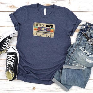 May include: A navy blue t-shirt featuring a vintage cassette tape graphic that reads "Best of 1976 40 Years of Being Awesome".