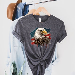 May include: A dark gray t-shirt with a graphic of a bald eagle with a red, white, and blue American flag design.