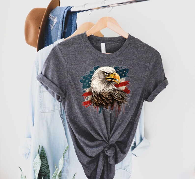 May include: A dark gray t-shirt with a graphic of a bald eagle with a red, white, and blue American flag design.