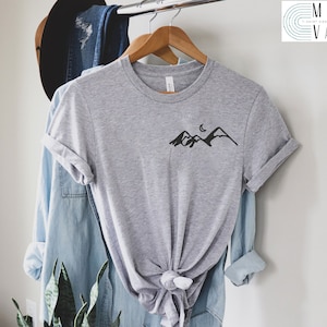 K&ouml;nnte beinhalten: Ein hellgraues T-Shirt mit einem schwarzen Bergpanorama und einem Halbmond-Motiv auf der Vorderseite.