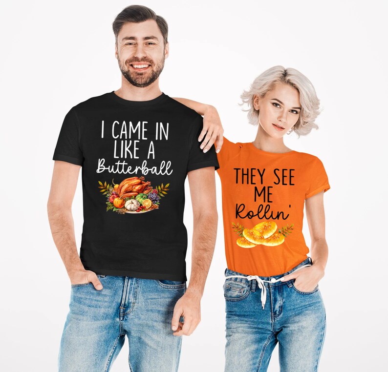 Puede incluir: Dos camisetas con dise&ntilde;os de Acci&oacute;n de Gracias. La camiseta negra dice "I came in like a Butterball" con un gr&aacute;fico de un pavo de Acci&oacute;n de Gracias y guarniciones. La camiseta naranja dice "They see me rollin'" con un gr&aacute;fico de panecillos.