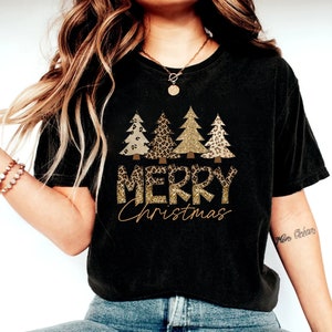 May include: Black t-shirt with a gold glitter "Merry Christmas" graphic featuring three Christmas trees with leopard print and gold glitter accents.