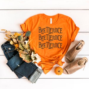 May include: Orange t-shirt with the text "Beetlejuice" repeated three times in black.