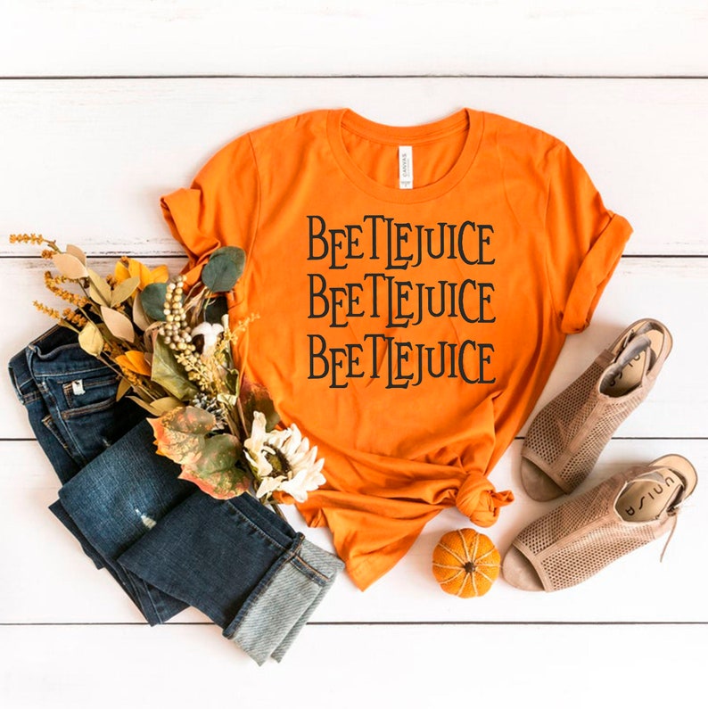 May include: Orange t-shirt with the text "Beetlejuice" repeated three times in black.