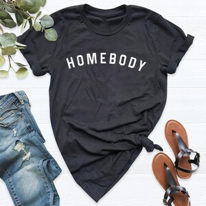 Puede incluir: Camiseta negra con texto blanco que dice "Homebody".