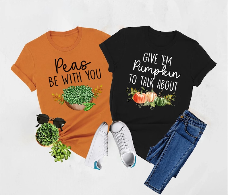 Puede incluir: Dos camisetas con dise&ntilde;os de oto&ntilde;o. La camiseta naranja dice "Peas Be With You" y presenta un taz&oacute;n de guisantes. La camiseta negra dice "Give 'Em Pumpkin To Talk About" y presenta tres calabazas.