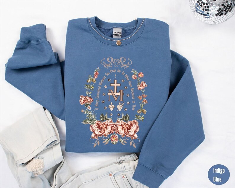 Puede incluir: Sudadera azul &iacute;ndigo con un dise&ntilde;o floral y el texto "Oh Mar&iacute;a, concebida sin pecado, ruega por nosotros que recurrimos a ti".