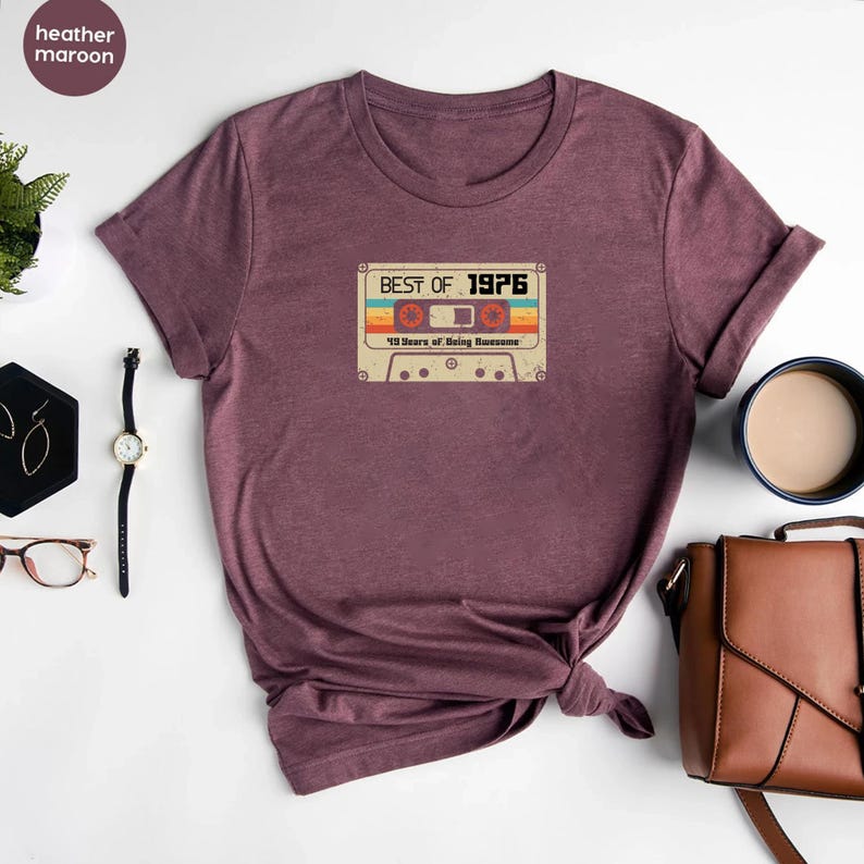 May include: Heather maroon t-shirt featuring a vintage cassette tape graphic that reads "Best of 1976 43 Years of Being Awesome".