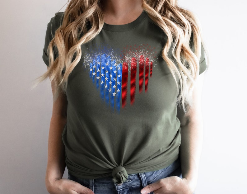 Pu&ograve; includere: T-shirt verde oliva con un design patriottico. La grafica presenta una bandiera americana stilizzata con stelle blu, strisce rosse e fuochi d'artificio bianchi. La maglietta &egrave; realizzata in materiale morbido e ha maniche corte.