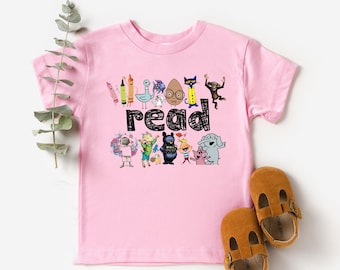 May include: Pink t-shirt with a graphic of characters from the book "The Book With No Pictures" and the text "Everybody read".
