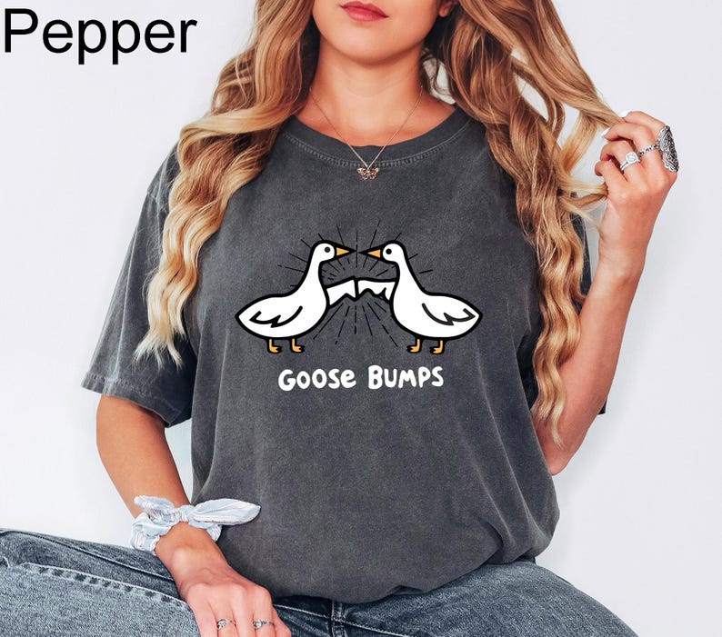 May include: A dark grey t-shirt with a white graphic of two geese facing each other with the text "Goose Bumps" underneath.