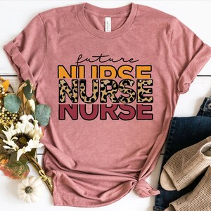 May include: A pink t-shirt with the text "future nurse" in orange, yellow, and red with a leopard print design.