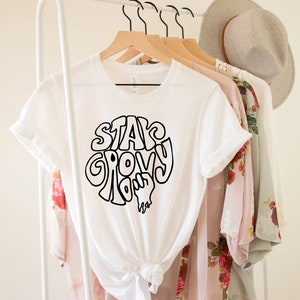 May include: White t-shirt with a black graphic that says "Stay Groovy" in a retro font.