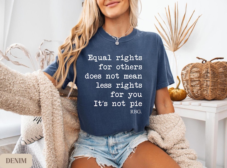 May include: A denim blue t-shirt with the quote "Equal rights for others does not mean less rights for you. It's not pie. RBG." in white lettering. The shirt is worn with denim shorts.