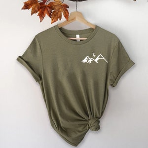 K&ouml;nnte beinhalten: Ein gr&uuml;nes T-Shirt mit kurzen &Auml;rmeln und einem wei&szlig;en Berg- und Halbmondmotiv auf der Vorderseite.