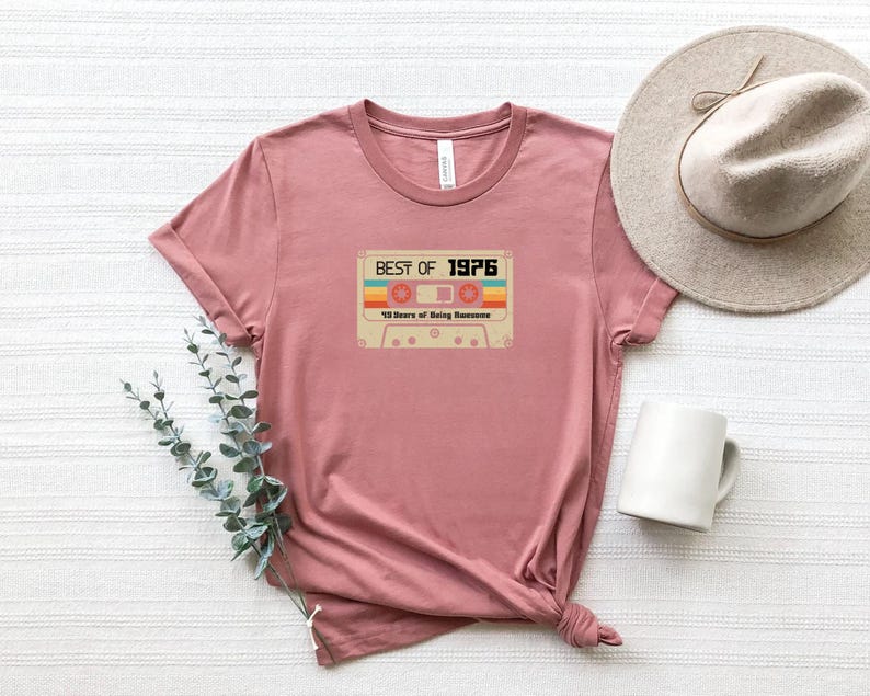 May include: A pink t-shirt featuring a vintage cassette tape graphic that reads "Best of 1976" and "43 Years of Being Awesome".