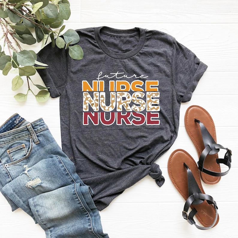 May include: A dark gray t-shirt with the text "future nurse" in orange, white, and maroon. The word "nurse" is repeated twice, with the second instance featuring a leopard print pattern.