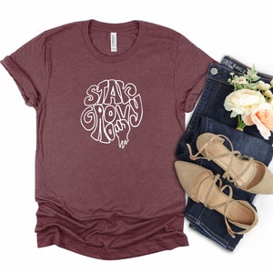 May include: A maroon t-shirt with a white graphic that says "Stay Groovy Baby".