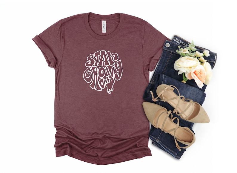May include: A maroon t-shirt with a white graphic that says "Stay Groovy Baby".